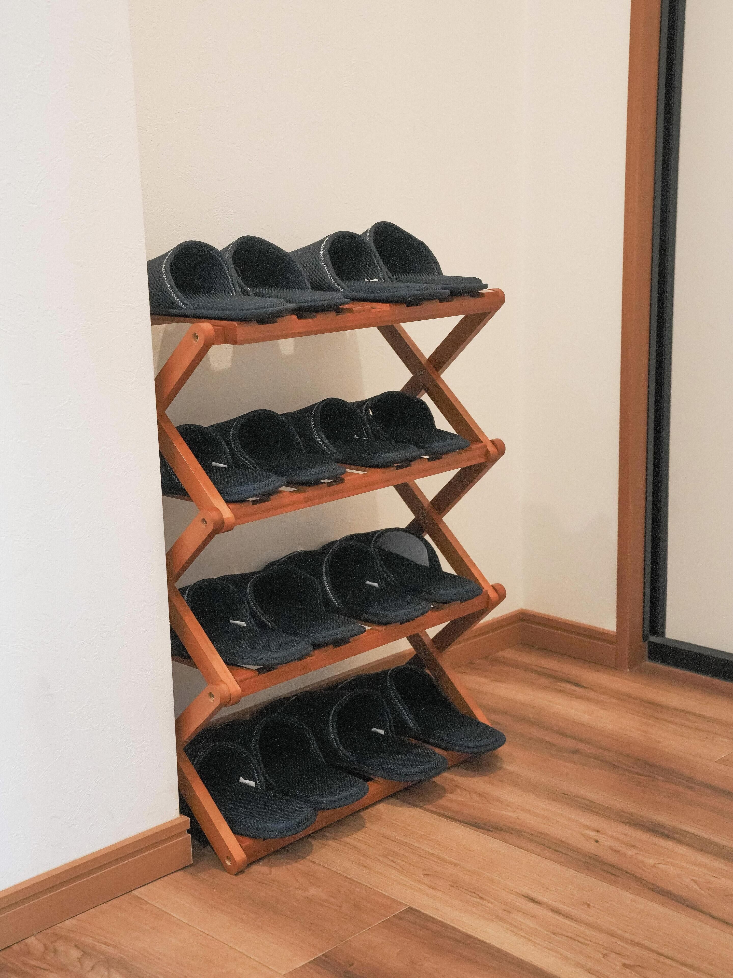 Un porte-chaussures en bois, doté de plusieurs étagères où sont rangées des chaussures noires.