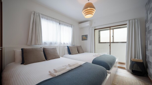 Une chambre d’hôtel avec deux lits, une grande fenêtre et une vue sur l’extérieur.