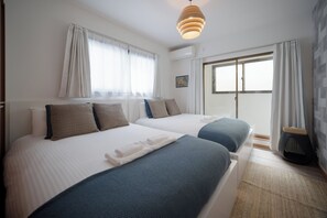 Een hotelkamer met twee bedden, een groot raam en uitzicht op de omgeving.