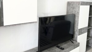 A modern living room with a flat-screen TV on a built-in shelf, white cabinets, and grey stone accents. - Sea and Beach (Puerto del Carmen)