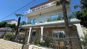 Une maison à deux étages dotée d’un balcon, d’une façade en pierre et d’un portail en métal.