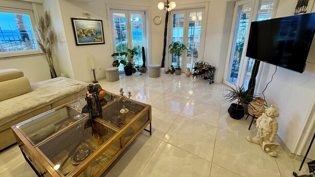 Un salon spacieux avec une table basse en verre, un canapé et un téléviseur fixé au mur.