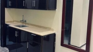 Una cucina compatta con mobili neri, un lavandino e un grande specchio.