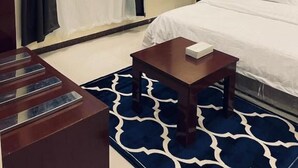 Una camera d'albergo con un letto, un comodino, una scrivania e un'ampia finestra con tende.