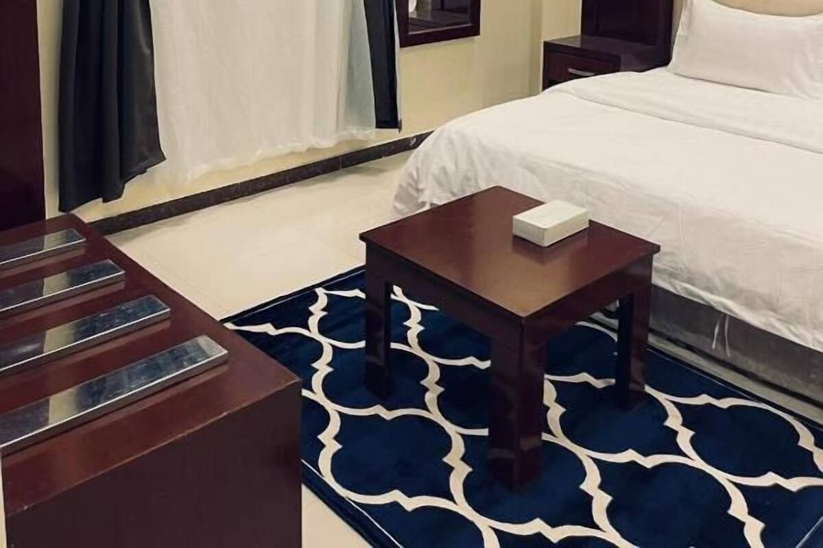 Une chambre d’hôtel avec un lit, une table de chevet, un bureau et une grande fenêtre avec des rideaux.