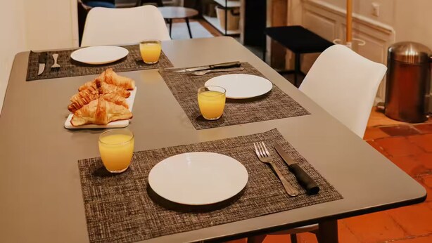A dining area with a table set for two, including plates, cutlery, and croissants. - Le Réaumur | Hyper Centre & Extérieur (La Rochelle)