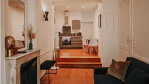 A modern living room with a fireplace, a sofa, and a dining area with chairs. - Le Réaumur | Hyper Centre & Extérieur (La Rochelle)