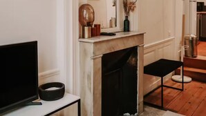 A modern living room with a fireplace, a television on a stand, and a dining table. - Le Réaumur | Hyper Centre & Extérieur (La Rochelle)