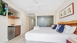 Une chambre moderne avec un grand lit, un ventilateur de plafond, une télévision et une vue sur une cascade.