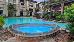 Un hôtel doté d’une piscine, entourée d’une végétation luxuriante et de palmiers.