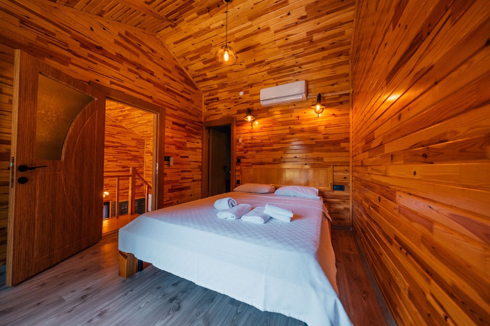 Une pièce de style cabane en bois, comprenant un lit, deux tables de chevet et un banc intégré.