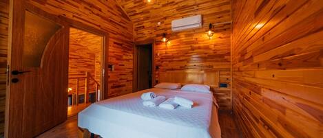 Une pièce de style cabane en bois, comprenant un lit, deux tables de chevet et un banc intégré.