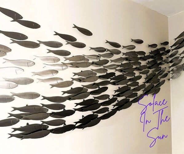 Pared con un diseño de siluetas de peces en diferentes tonos de gris.