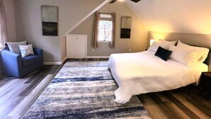 Ein Schlafzimmer mit einem großen Bett, einem Deckenventilator, einer kleinen Sitzecke und einem Fenster.