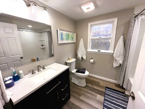 Un baño moderno con un espejo grande, dos lavamanos, un inodoro y una ventana.