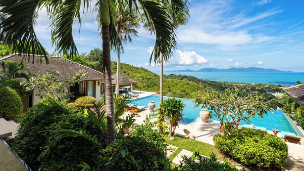 A pool surrounded by lush greenery and palm trees, with a view of the ocean and mountains in the background. - Ban Reemo Luxury Villa (Surat Thani)