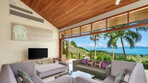 A modern living room with a large TV, comfortable seating, and a view of the ocean. - Ban Reemo Luxury Villa (Surat Thani)