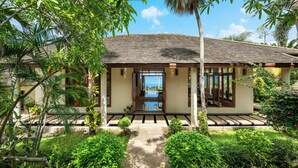 A tropical resort with a covered walkway leading to a building with large windows and a view of the ocean. - Ban Reemo Luxury Villa (Surat Thani)