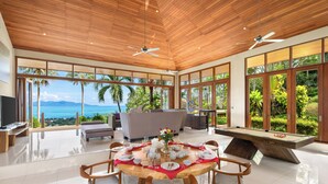 A spacious room with a pool table, dining table set for four, and a large window offering a view of the ocean. - Ban Reemo Luxury Villa (Surat Thani)