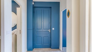 A hallway with a blue door, white walls, and a light switch on the wall. - BELLE DARSE AP4454 By Riviera Holiday Homes (Villefranche-sur-Mer)