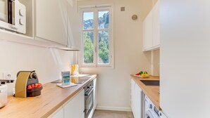 A compact kitchen with a built-in oven, a microwave, and a washing machine. - BELLE DARSE AP4454 By Riviera Holiday Homes (Villefranche-sur-Mer)