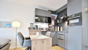 A modern kitchen with a flat-screen TV, Bosch appliances, and a dining area with a wooden table and chairs. - Strandschlösschen Apartment 27 (Haffkrug)