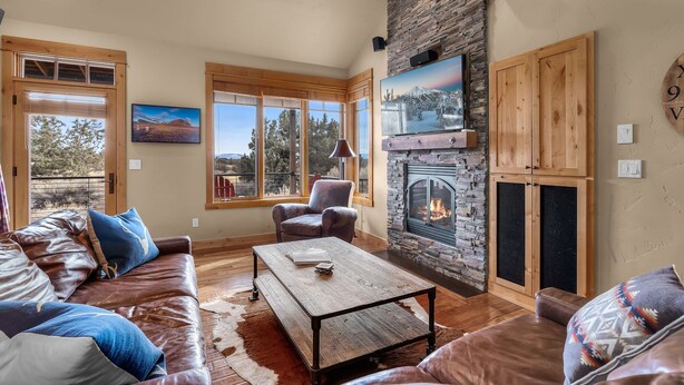 Una sala de estar acogedora con chimenea de piedra, mobiliario de cuero y amplias ventanas con vistas panorámicas.