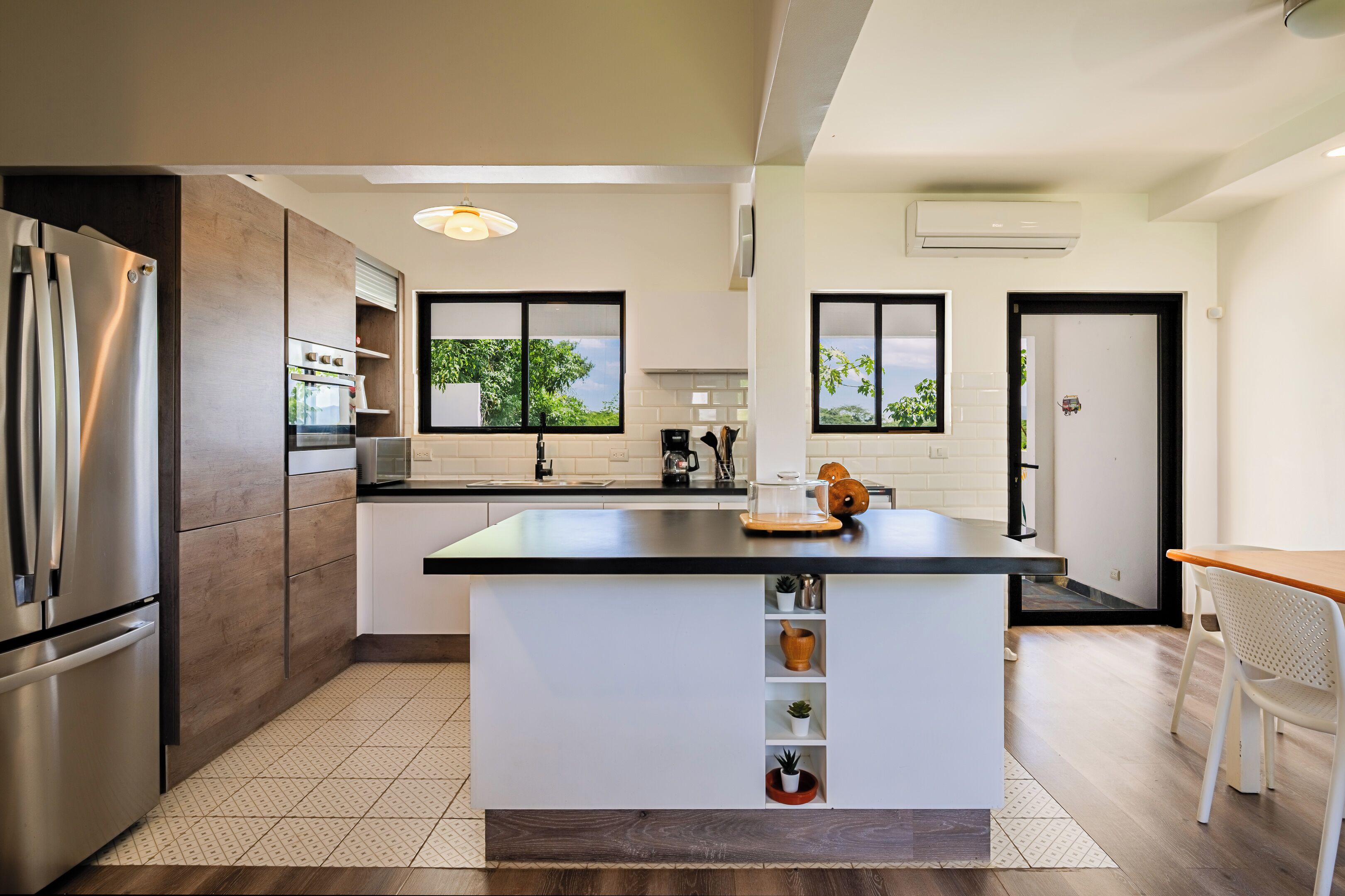 A modern kitchen with a central island, built-in appliances, and large windows.