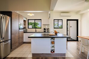 Una cocina moderna con una isla central, electrodomésticos integrados y ventanas amplias.