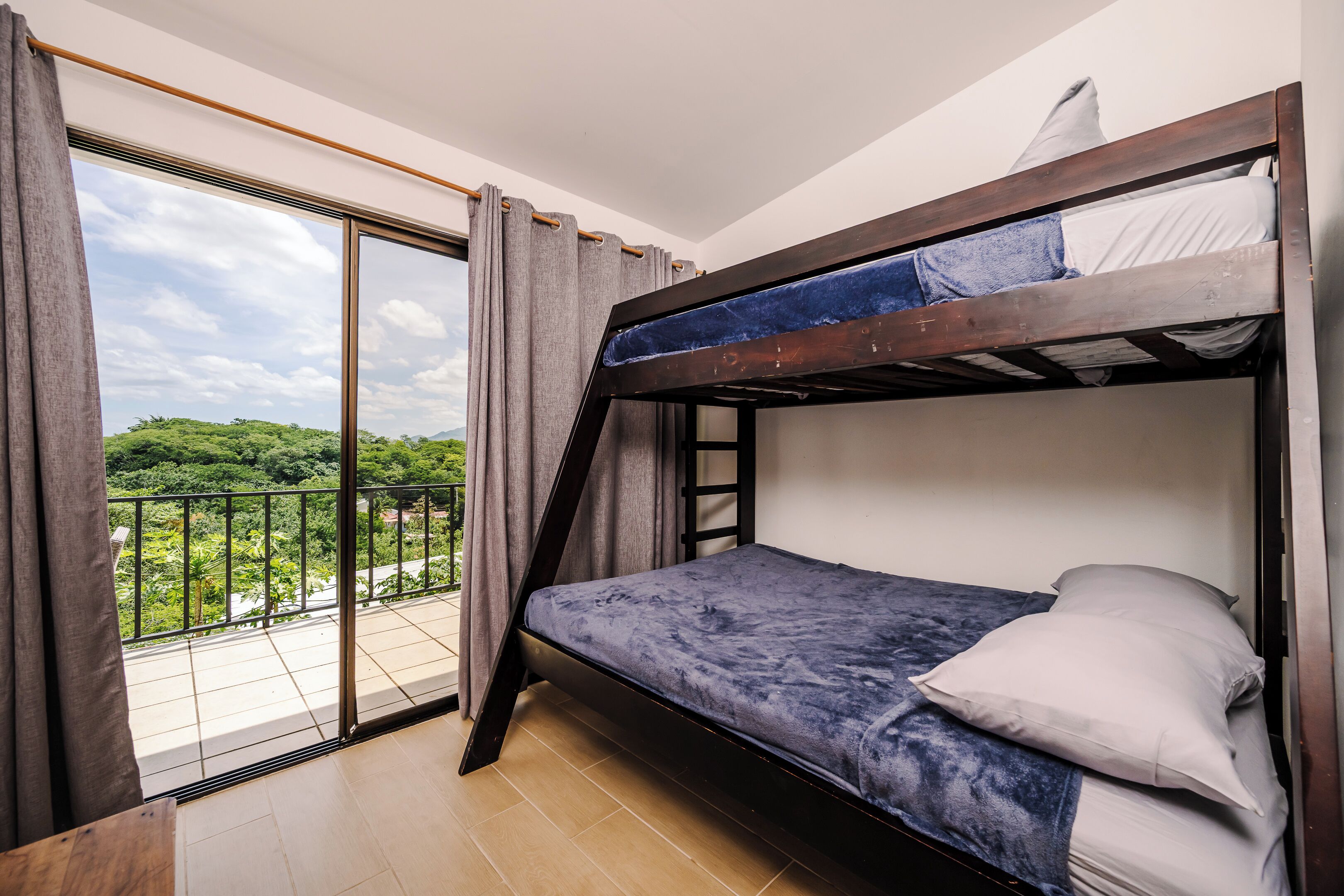 A bunk bed room with a balcony and a view of greenery.
