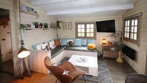 A cozy cabin interior with a wooden interior, a sofa bed, a coffee table, and a television.