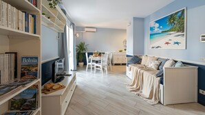 A living room with a sofa, a dining table, and a bookshelf. - Imperia City apartment (Imperia)