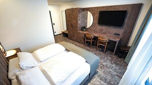 A hotel room with a bed, a desk, and a TV. - JG Hotel Antoniergasse (Memmingen)