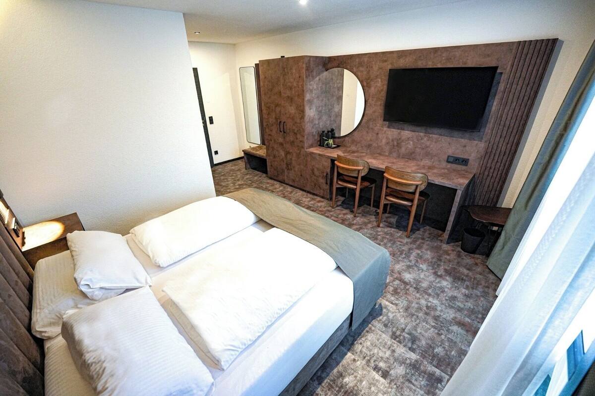 A hotel room with a bed, a desk, and a TV.