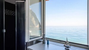 Una habitación con un ventanal grande que da a una masa de agua y un acantilado.