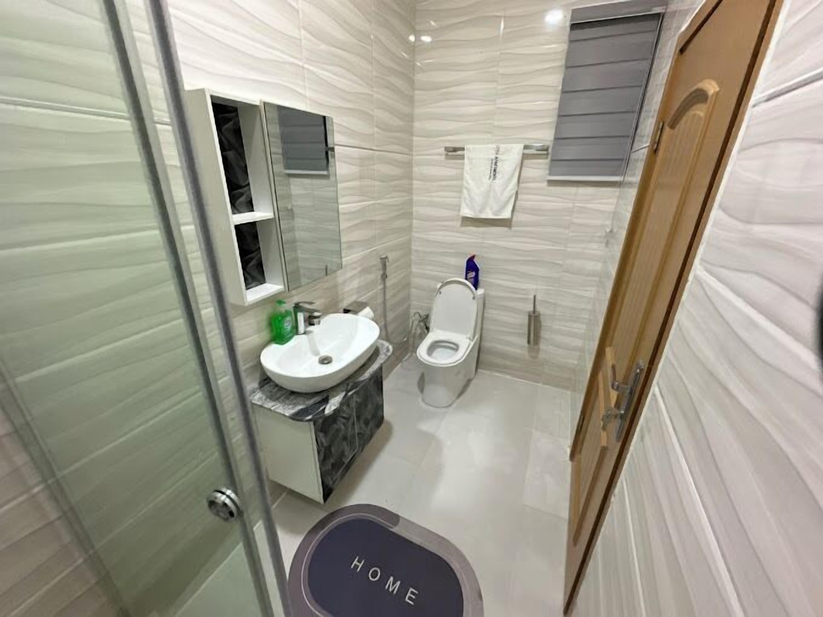 Une salle de bain moderne avec un lavabo en marbre, des toilettes et une douche à parois de verre.