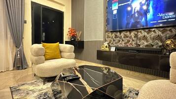 Een moderne woonkamer met een bank, een salontafel en een flatscreen televisie aan de muur.