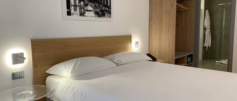 Ein modernes Hotelzimmer mit einem großen Bett, einem Nachttisch und einem Holzschrank.