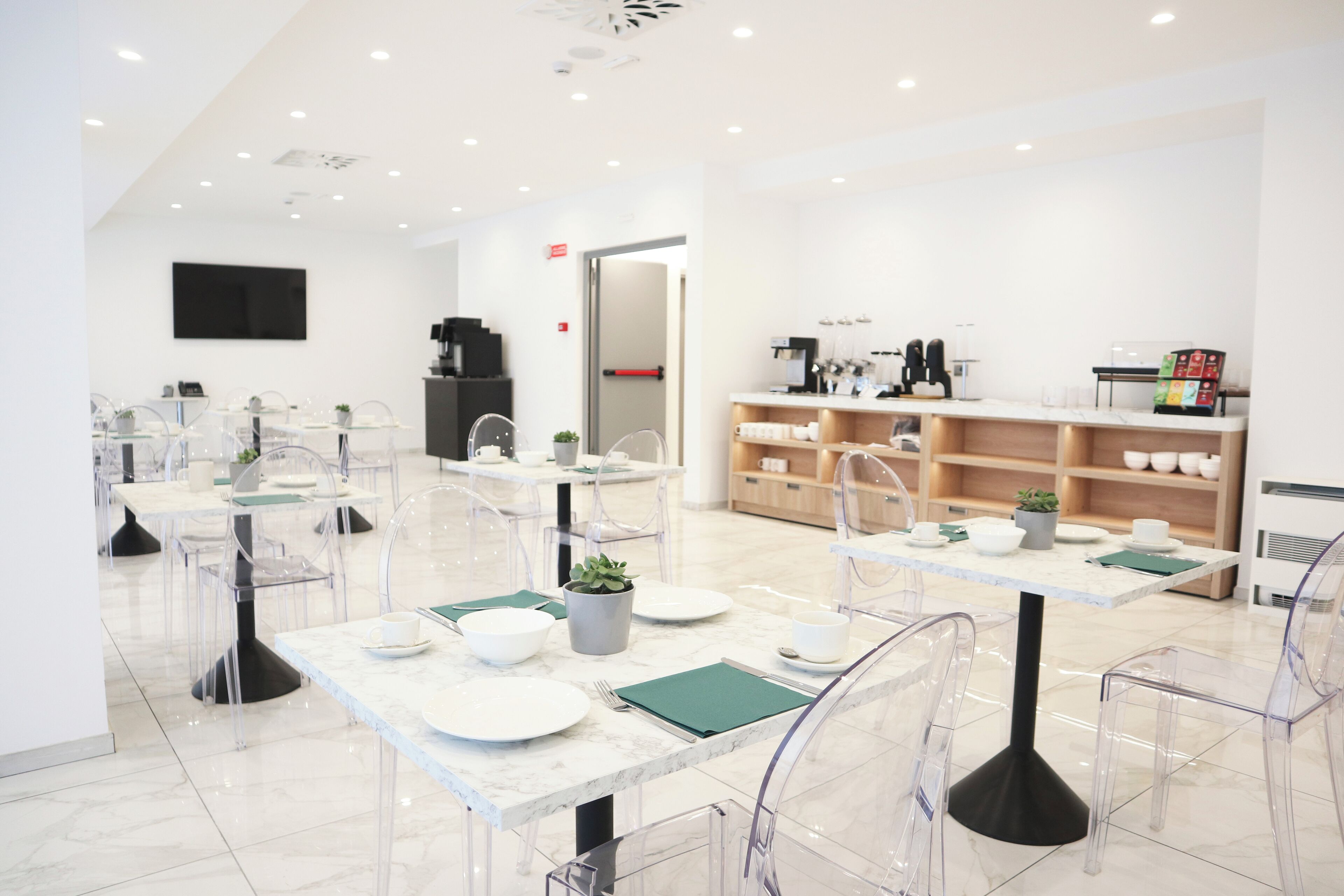 A modern dining area with clear chairs, white tables, and a minimalist design.