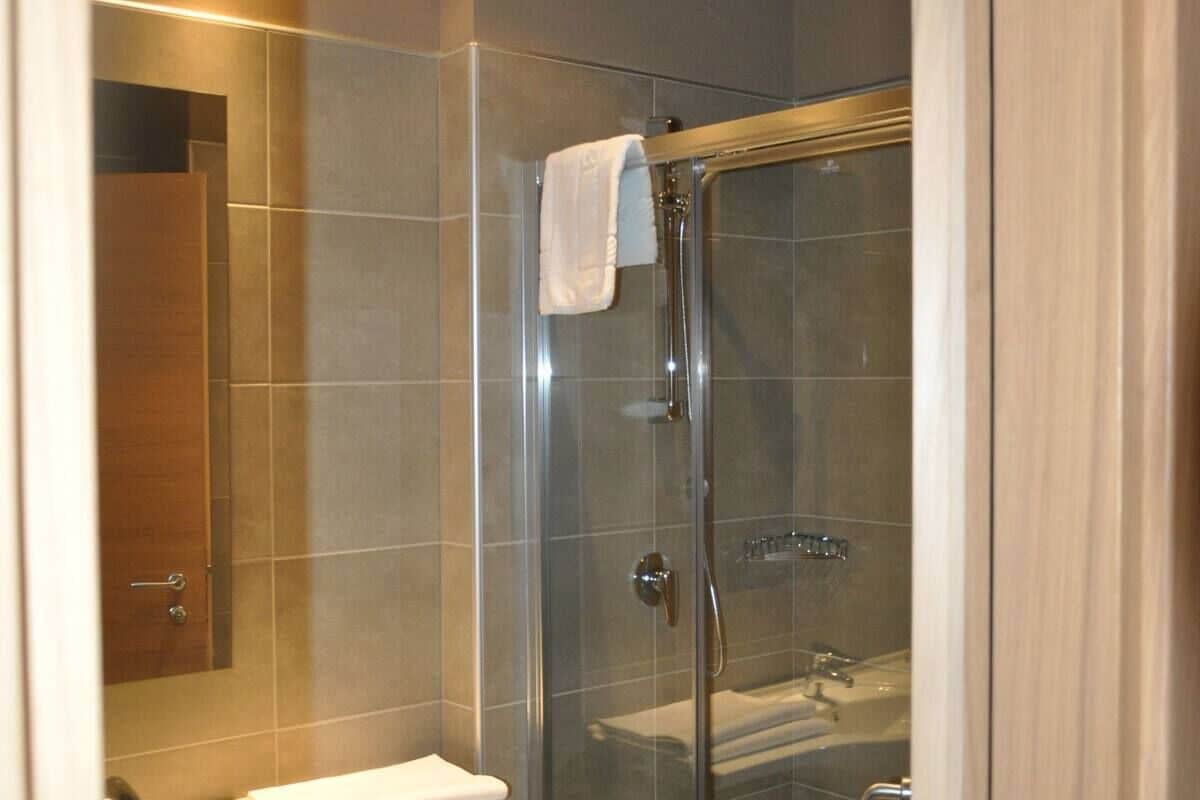 Ein modernes Badezimmer mit einer Duschkabine aus Glas, einer weißen Toilette und einem Spiegel.