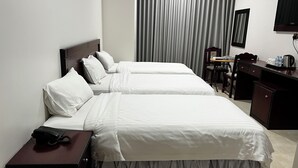 A hotel room with two beds, a desk with a telephone, a chair, a small table with a chair, a television, and a window with curtains. - Al Rayyan Hotel (Madinah)