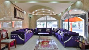 A spacious lobby with purple sofas, a central coffee table, and a large rug. - Al Rayyan Hotel (Madinah)