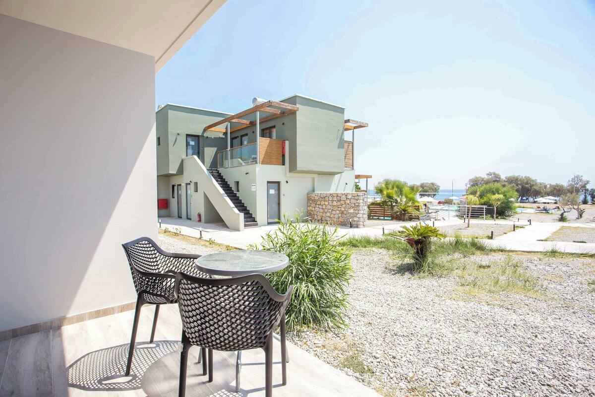 A modern two-story house with a balcony, a staircase, and a view of the sea.