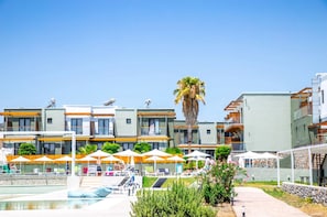 A modern hotel with a swimming pool, outdoor umbrellas, and a palm tree. - Gennadi Sea Side Resort (Rhodes)