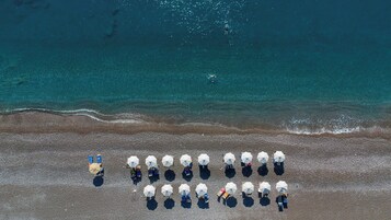 En la playa, sillas reclinables de playa, sombrillas, toallas de playa