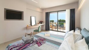 A modern hotel room with a large bed, a desk, a flat-screen TV, and a balcony with a view. - Gennadi Sea Side Resort (Rhodes)
