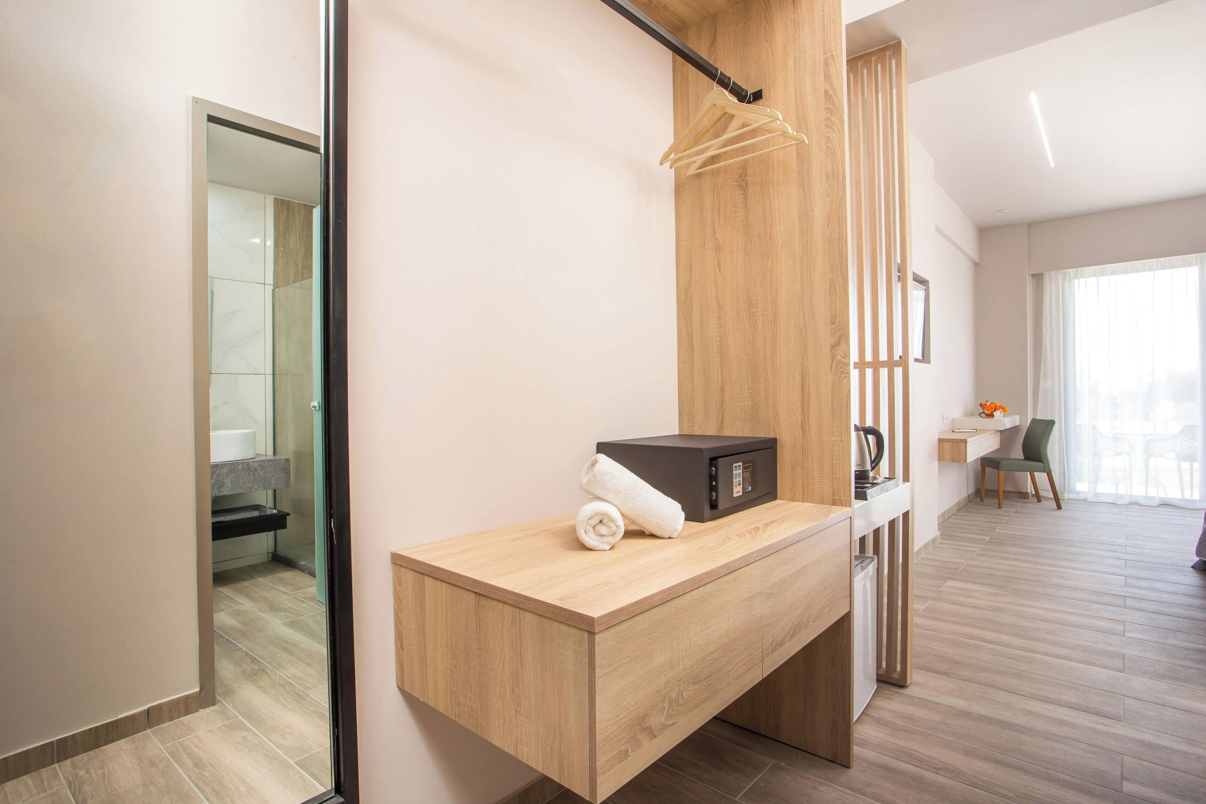 A modern hotel room with a wooden desk, a black safe, and a towel.