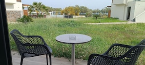 A patio area with two chairs and a table, surrounded by a grassy garden and a stone wall. - Gennadi Sea Side Resort (Rhodes)