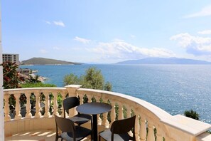 A balcony with a view of the sea, two chairs, and a small table. - Apartments Romario  (Sarande)