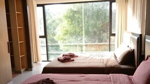 Een hotelkamer met twee bedden, een groot raam en een kledingkast.